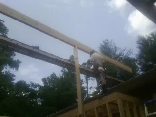 Carpenter setting a ridge beam over a new addition frame — Ice Dam Removal by Roofing Brothers in Arnold