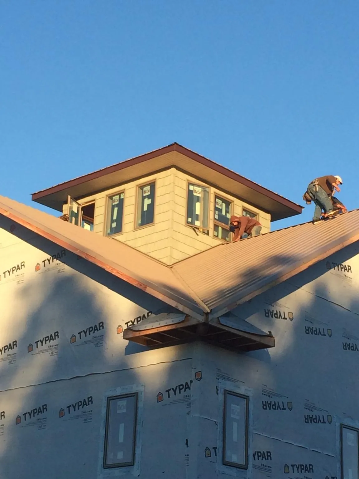 Roofers working around a rooftop cupola on a new metal roof at sunset — Roof Waterproofing in Arnold by Roofing Brothers